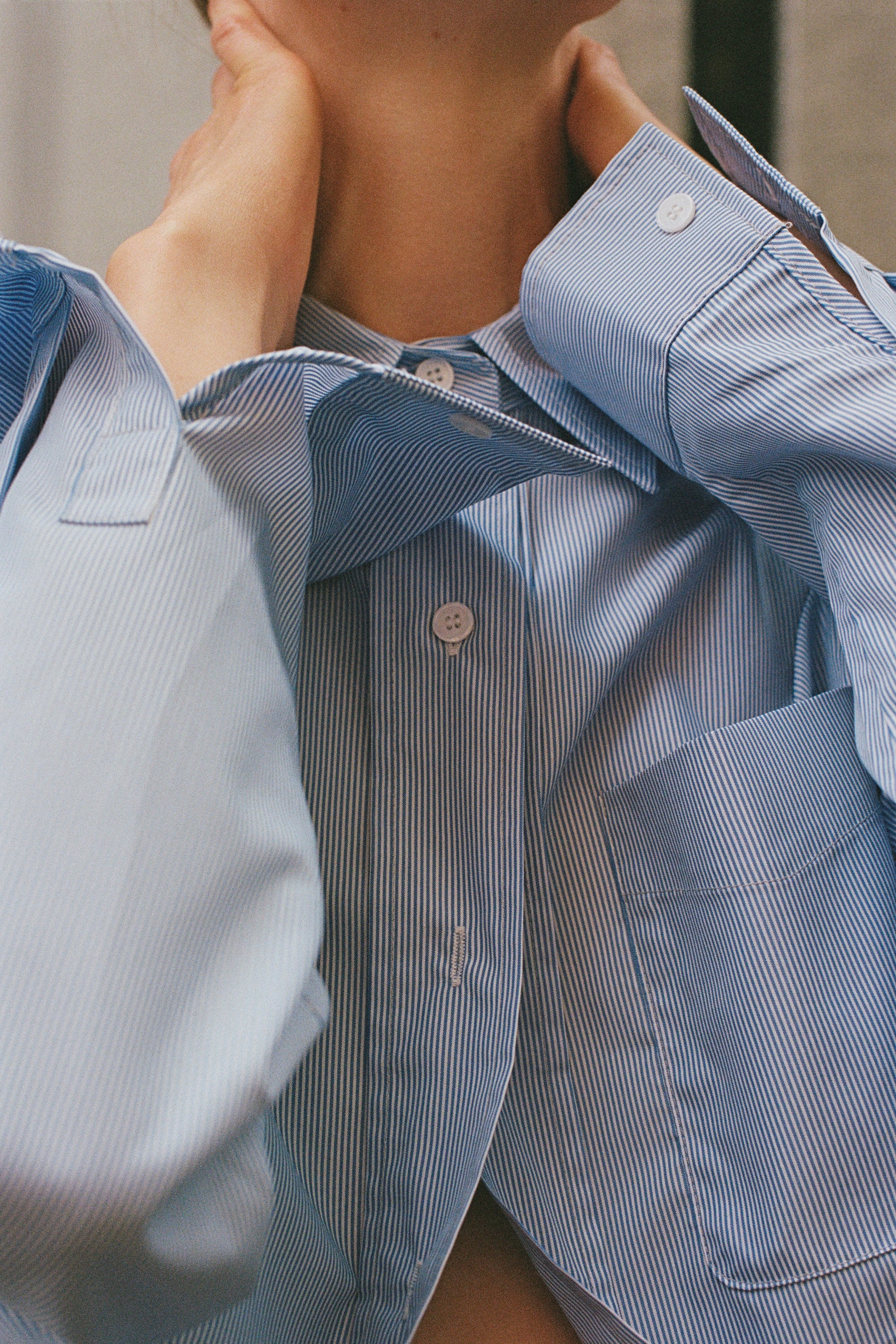 A close up a model wearing the Frankie Shop Blue stripped shirt.