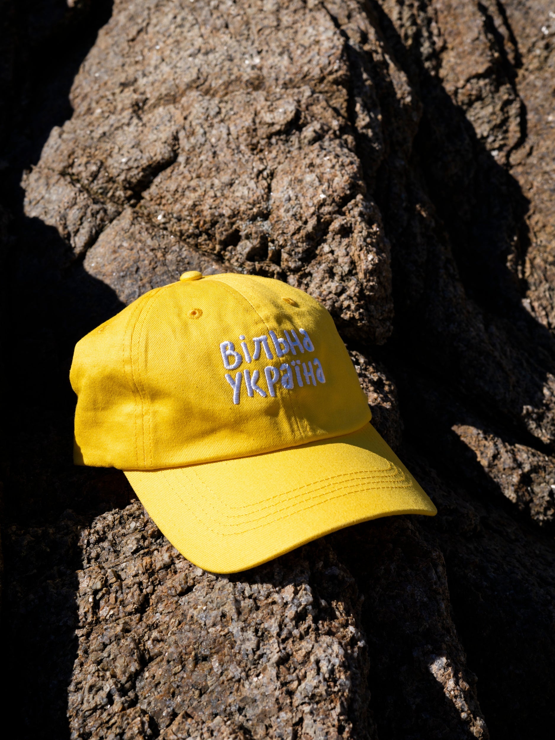 Yellow cap photographed on the rocks with the slogan "Free Ukraine" embroidered on it.