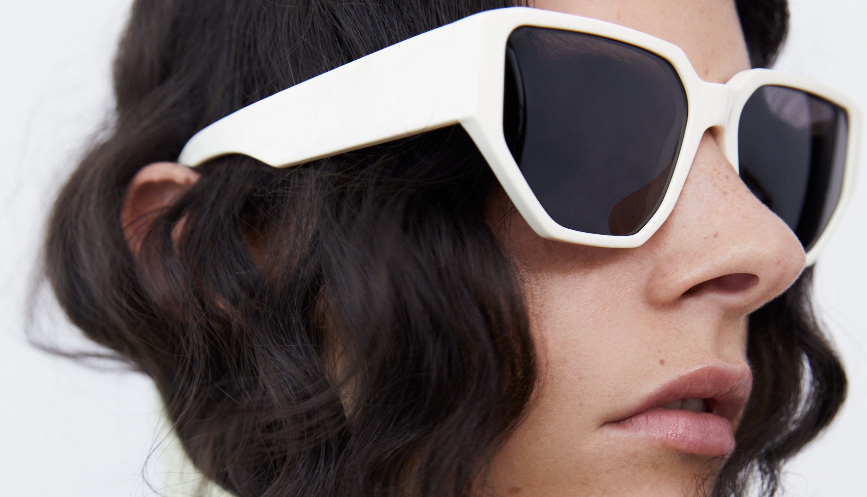 Close up of a Model photographed by Suzanne Koller wearing white sunglasses for the FW21 campaign. 