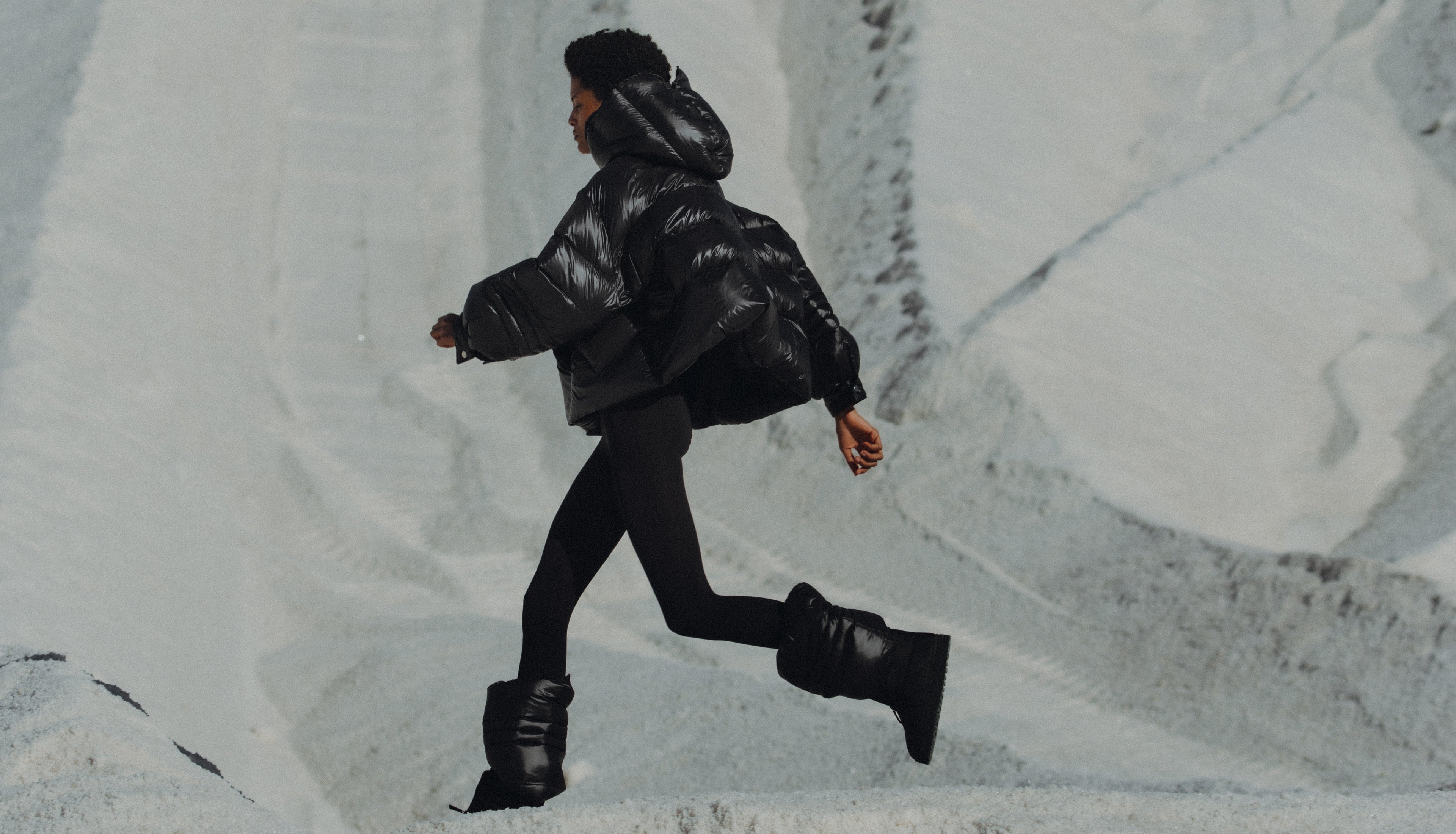 Model sanding on the snow capped mountain wearing the Val puffer jacket. Photographed by Charlotte Lapalus