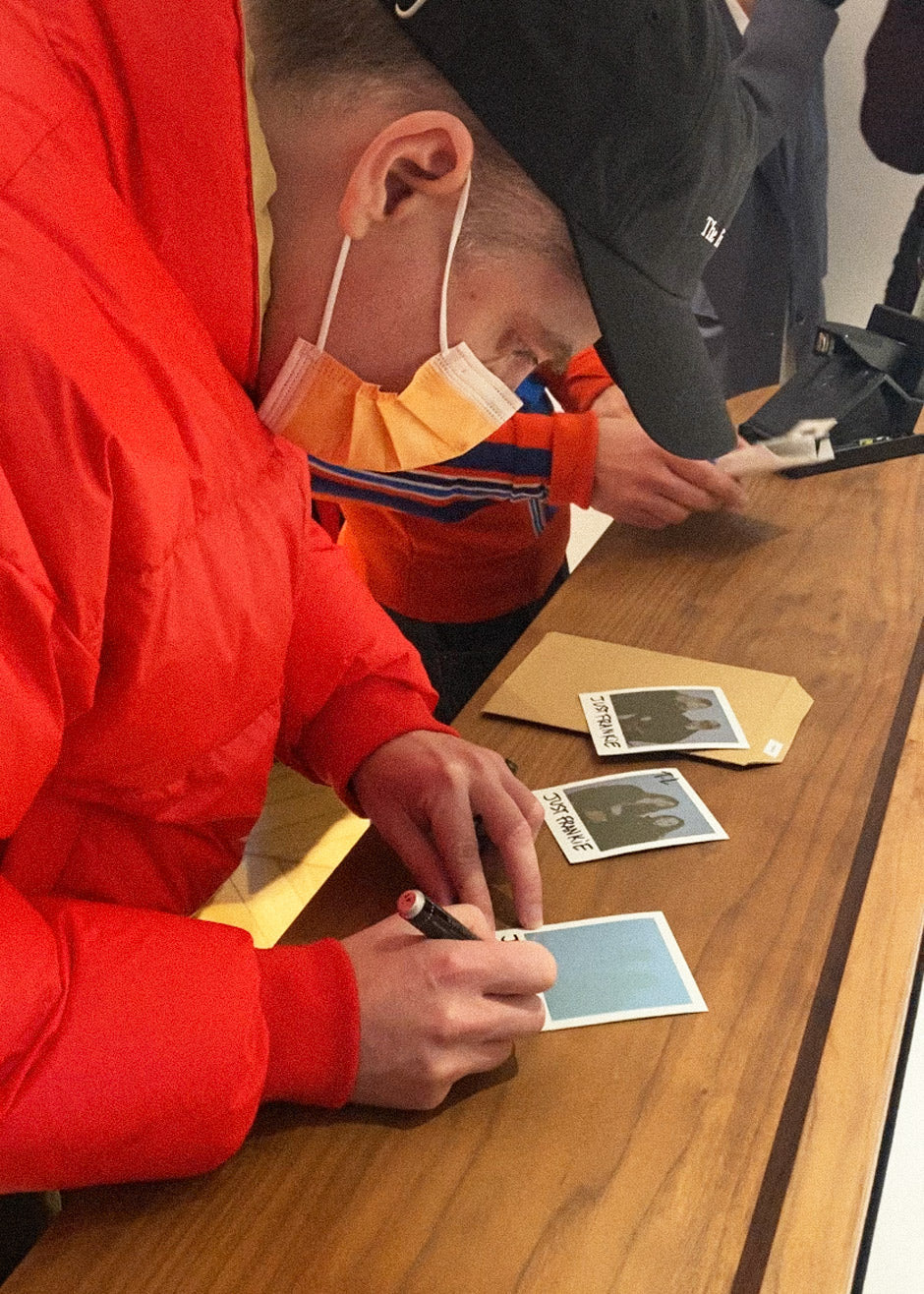 Thomas Lelu hand writing "Just Frankie" on the polaroids at The Frankie Shop event