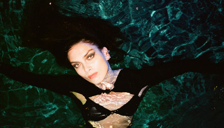 Model photographed in the water wearing the coperni cut out jersey bodysuit.