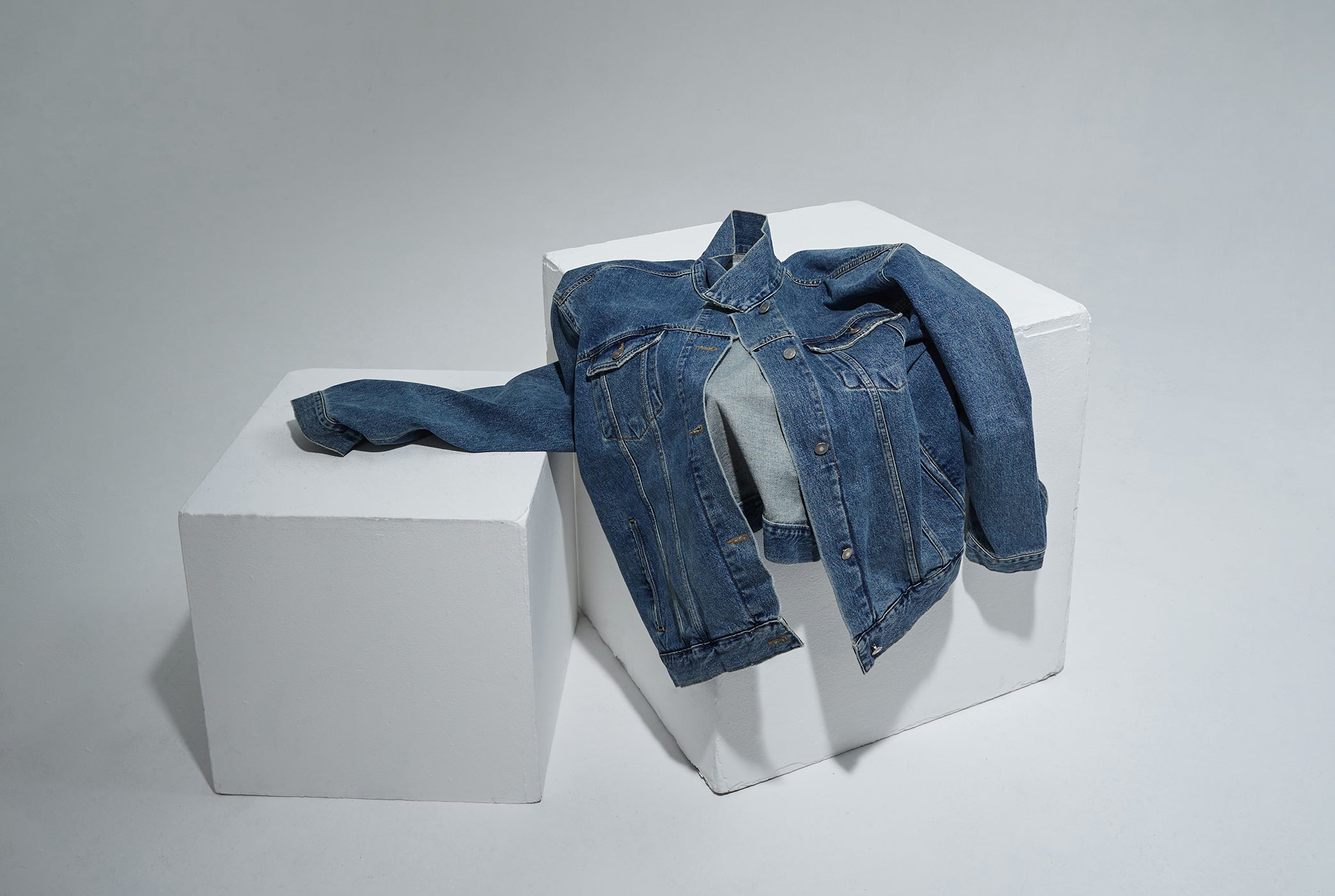 Image of the Texas boxy jacket in denim places over white blocks. 