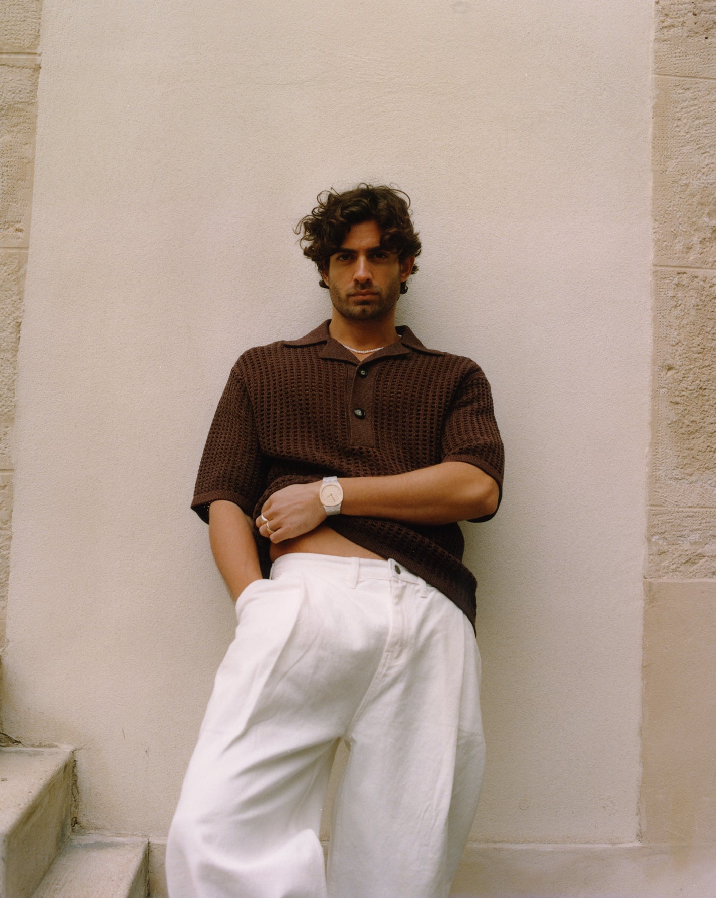 Male model wearing the Frankie Shop Drew denim pants and a brown knitted t-shirt. 