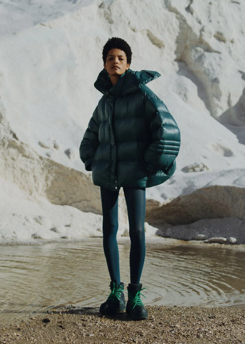 Model sanding on the snow capped mountain wearing the Val puffer jacket. Photographed by Charlotte Lapalus