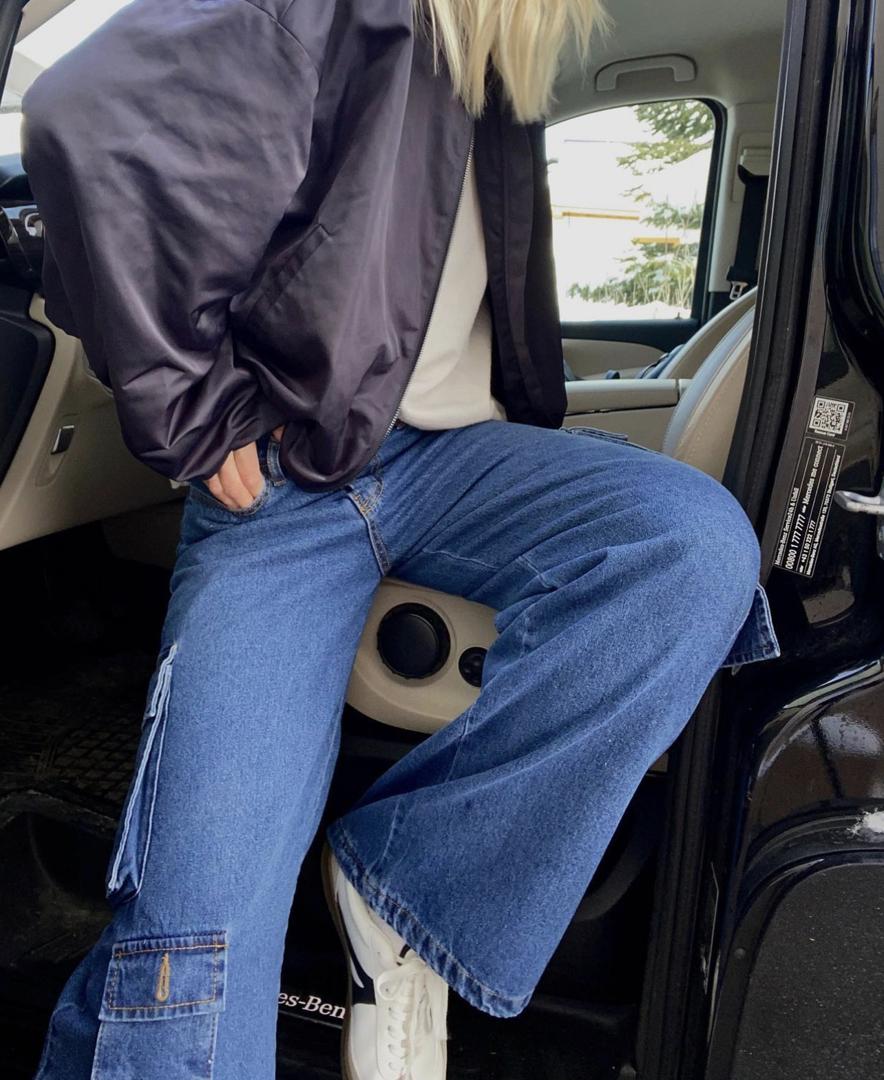 Model coming out of a car wearing the Frankie Shop Kai cargo denim pants in worn wash. 